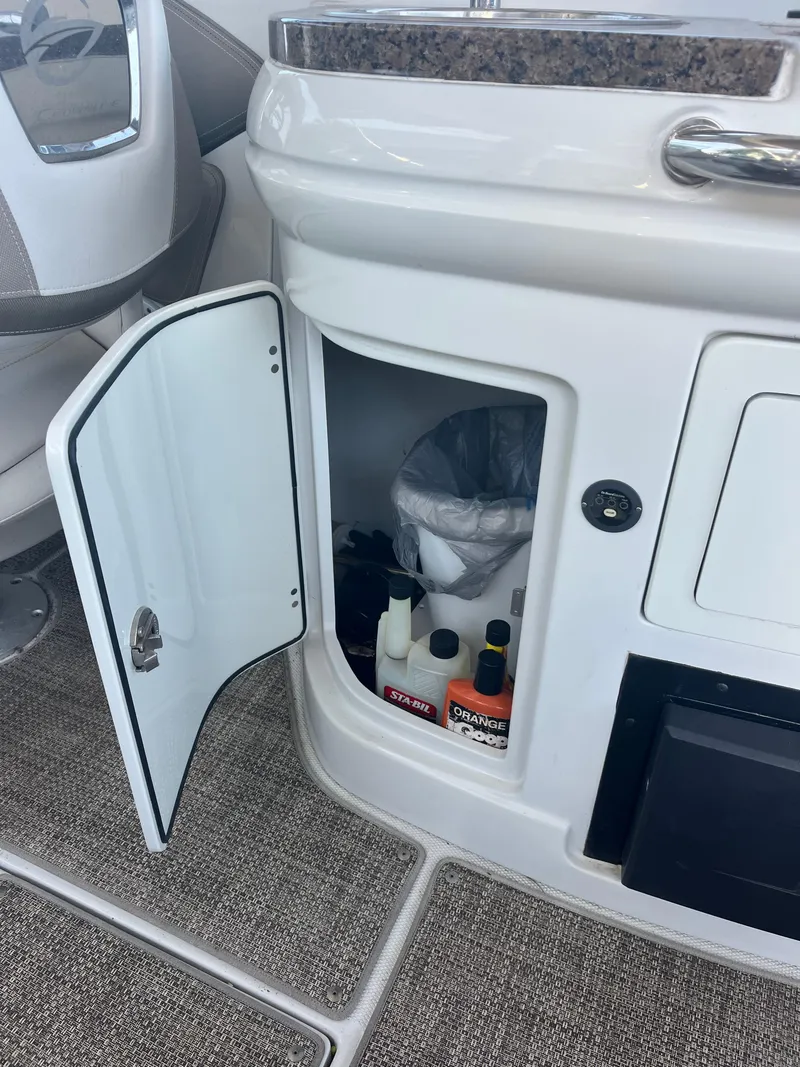 Slide: The Image of Open storage compartment on 2020 Crownline 280 XSS boat with cleaning supplies inside. - 10