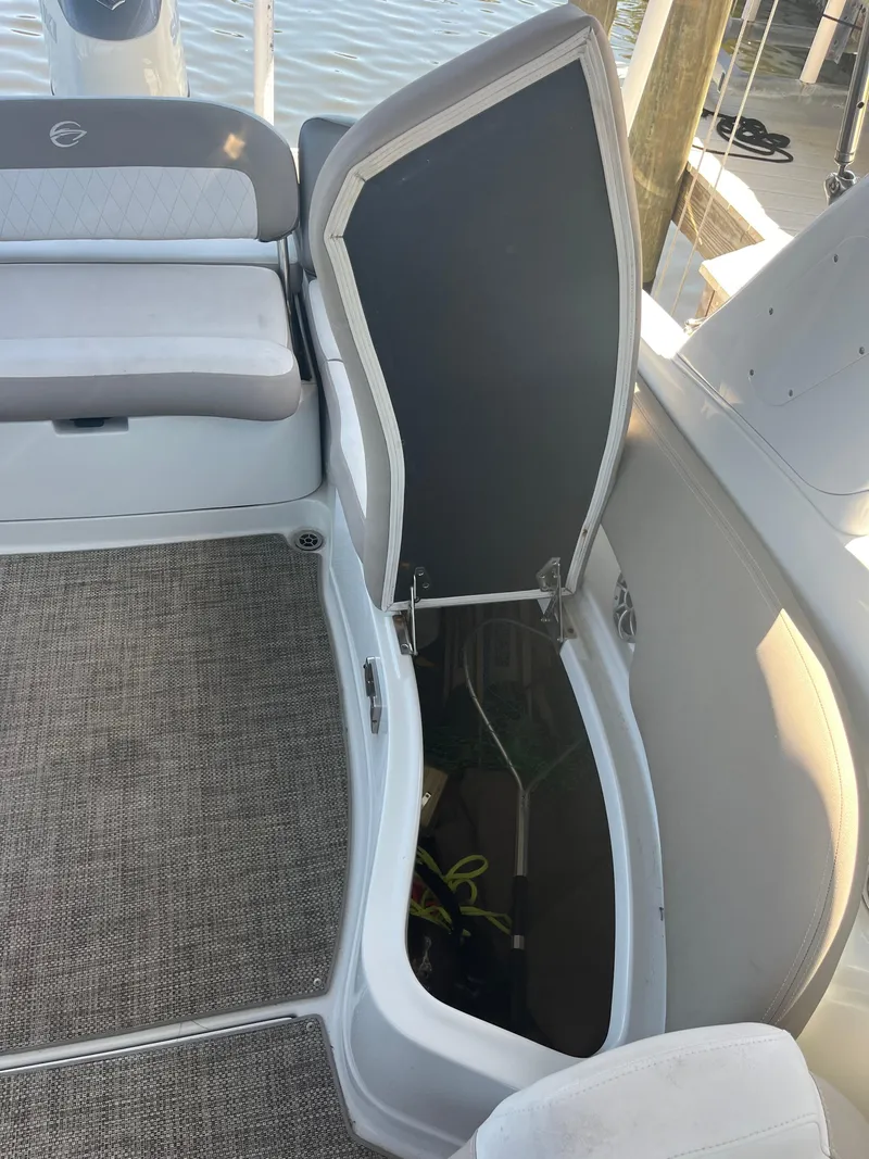Slide: The Image of 2020 Crownline 280 XSS boat with open storage compartment, gray seating, and carpeted floor. - 22
