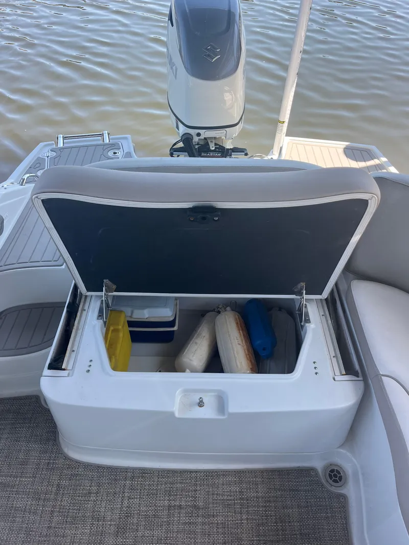 Slide: The Image of 2020 Crownline 280 XSS boat storage compartment with various items, near water. - 23