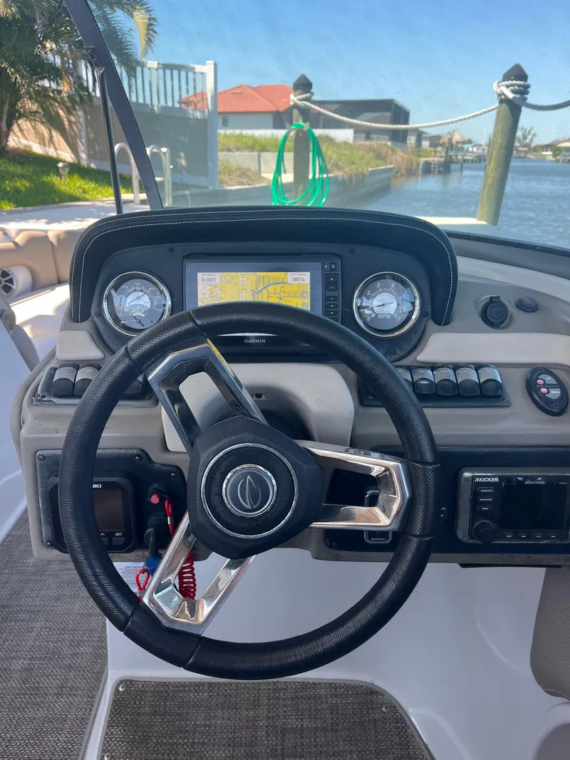 Slide: The Image of Steering wheel and dashboard of 2020 Crownline 280 XSS boat, docked by the water. - 25