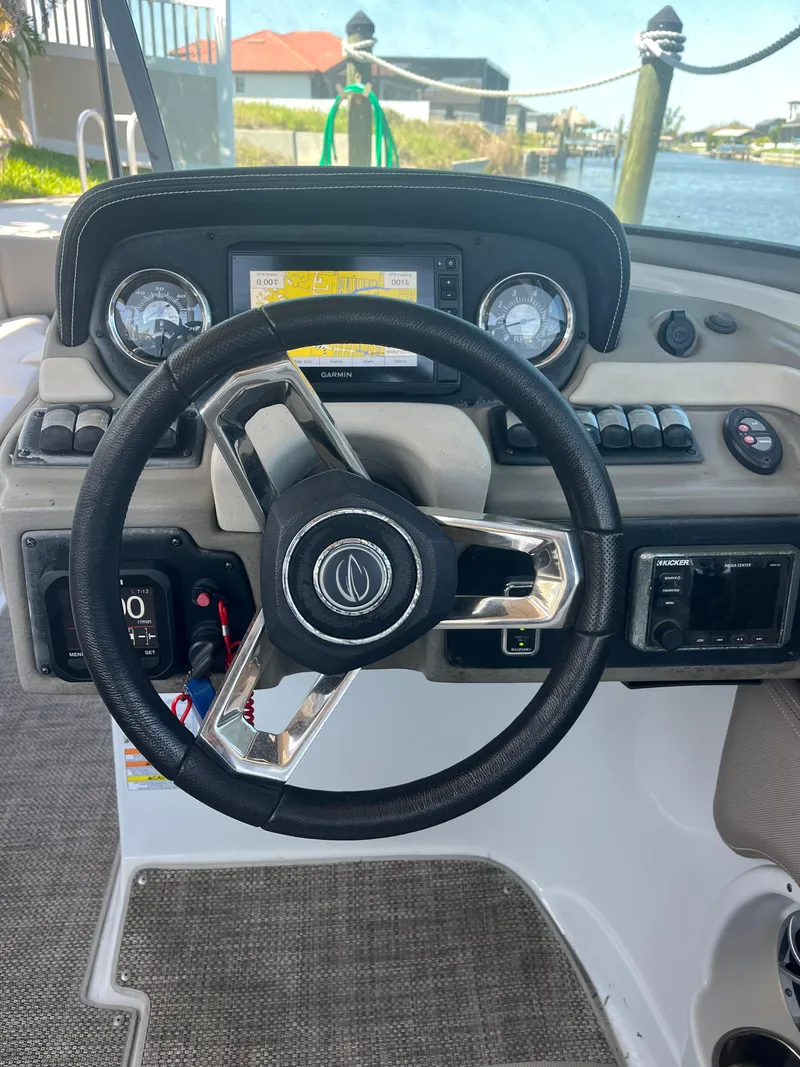 Slide: The Image of Steering wheel and dashboard of 2020 Crownline 280 XSS boat, docked by the water. - 6