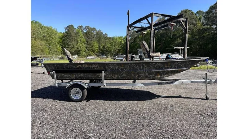Slide: The Image of 2025 War Eagle 648LDV Sportsman boat on trailer, parked outdoors. - 2