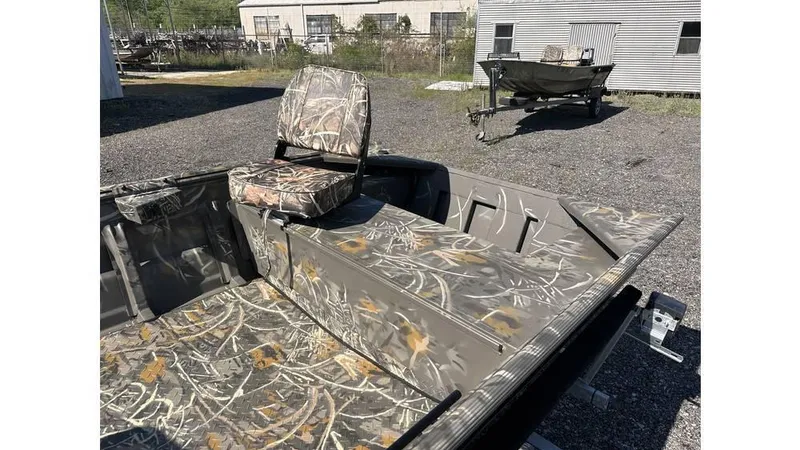 Slide: The Image of 2025 War Eagle 648LDV Sportsman boat with camouflage seating and interior, parked outdoors. - 8