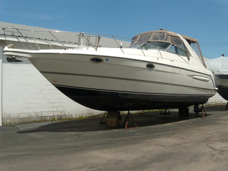 The Image of 2000 Maxum 3300 SCR boat on stands, white hull, outdoor storage. - 0