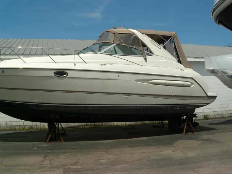 Slide: The Image of 2000 Maxum 3300 SCR boat on stands, beige exterior, parked outdoors. - 1