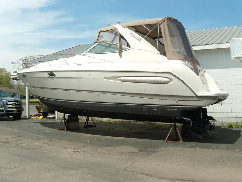 Slide: The Image of 2000 Maxum 3300 SCR boat on stands, beige canopy, parked outdoors. - 2
