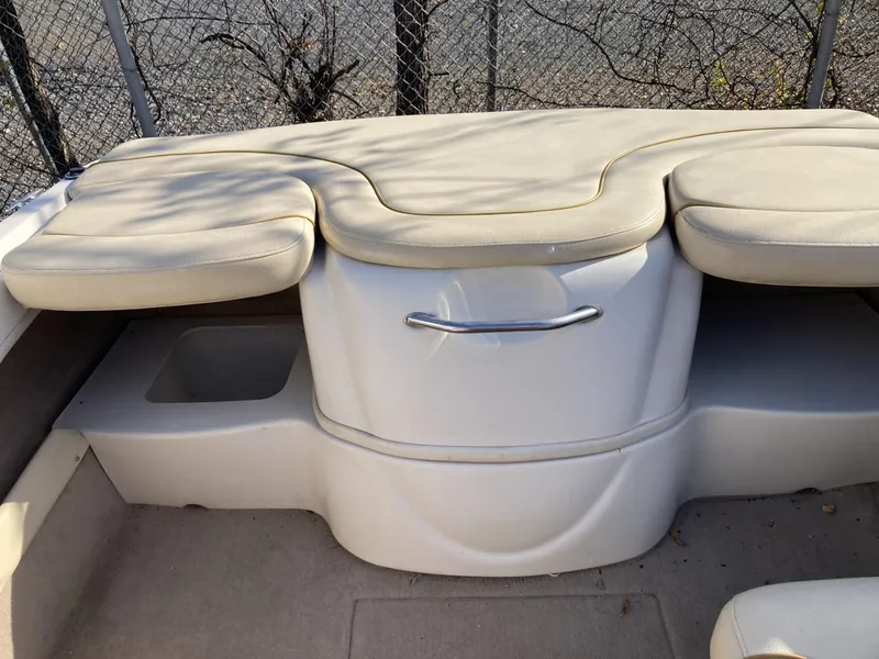 Slide: The Image of 2001 Sea Ray 180 Bow Rider interior seating with beige cushions and storage compartment. - 7