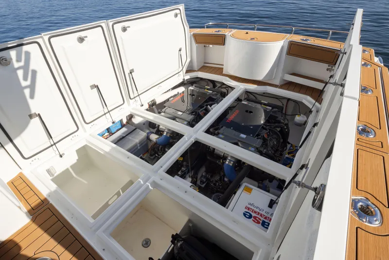 Slide: The Image of 2025 Ocean Sport Roamer boat engine compartment with open hatches, showcasing dual engines. - 29