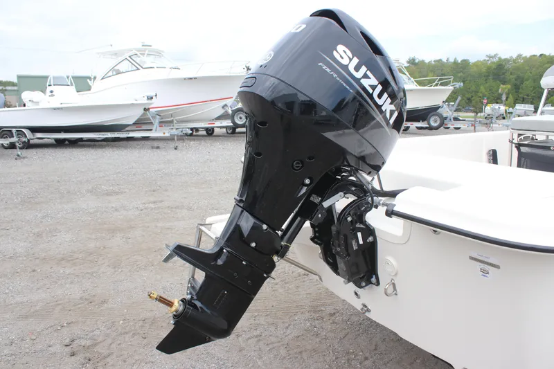 Slide: The Image of 2025 Carolina Skiff E18 JVX CC with Suzuki outboard motor, parked on gravel lot. - 10