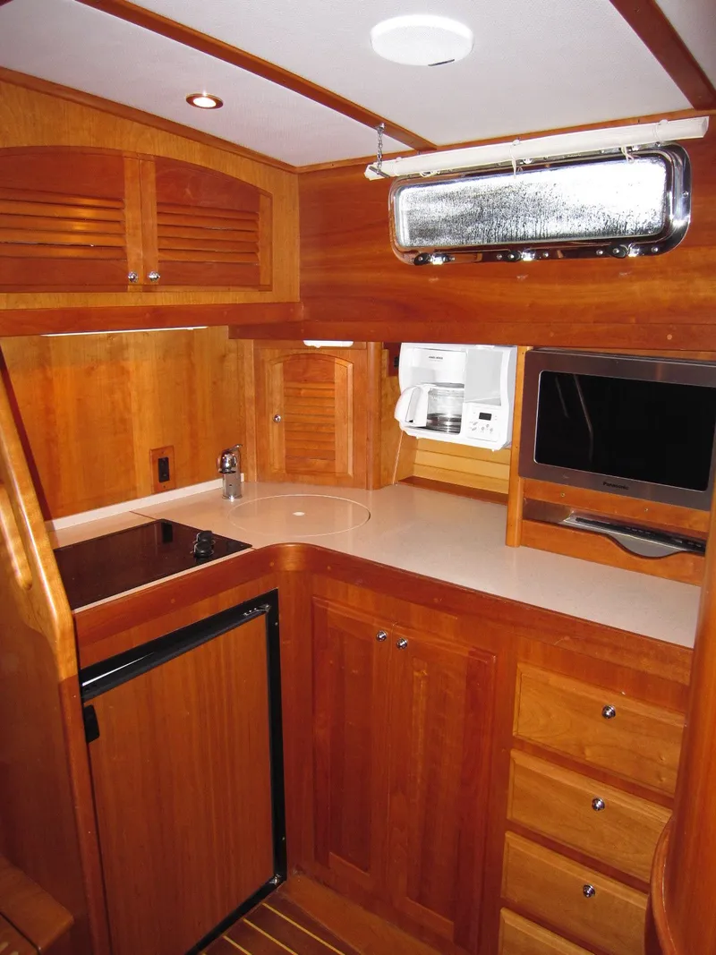 Slide: The Image of 2005 Sabre 38 yacht interior with wooden cabinetry, compact kitchen, and modern appliances. - 18