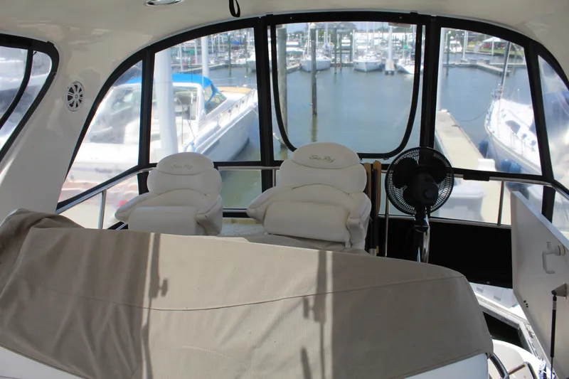 Slide: The Image of 2000 Sea Ray 480 Sedan Bridge interior with marina view, featuring comfortable seating and large windows. - 12
