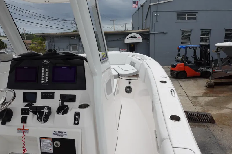 Slide: The Image of 2024 Sea Fox 268 Commander boat with modern dashboard and seating, docked near industrial buildings. - 14