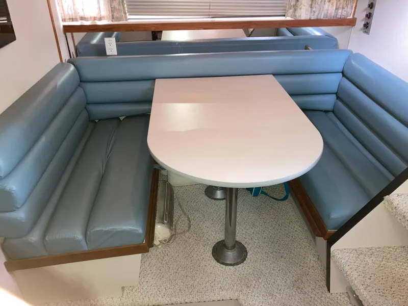 Slide: The Image of 1988 Carver 3257 Montego interior with blue cushioned seating and white table. - 7