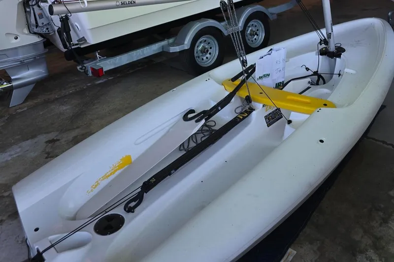 Slide: The Image of 2024 RS Sailing Zest boat in a garage, featuring a sleek white and yellow design. - 3