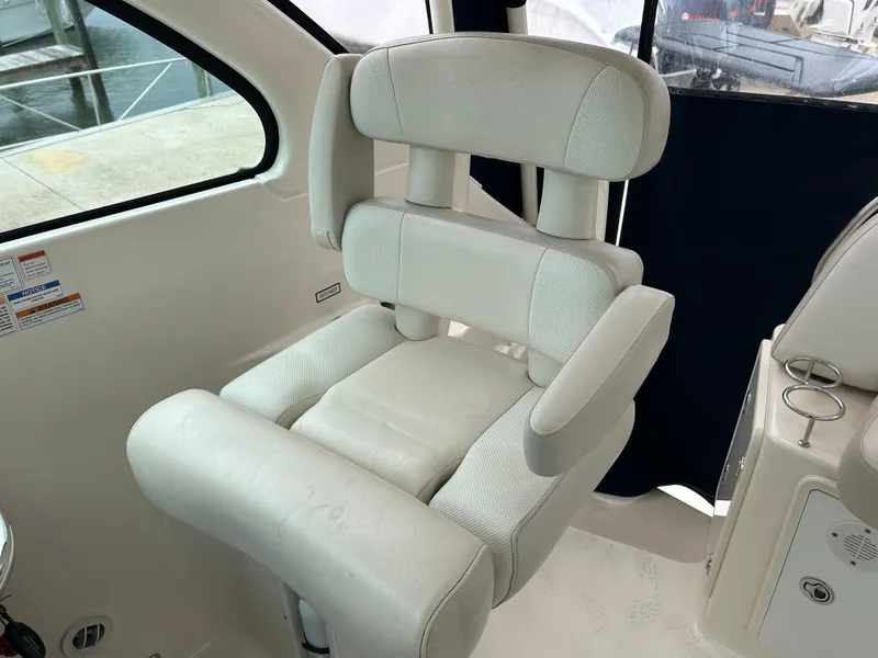 Slide: The Image of Captain's chair on 2011 Pursuit OS 315 Offshore boat, featuring white cushioned seating. - 12