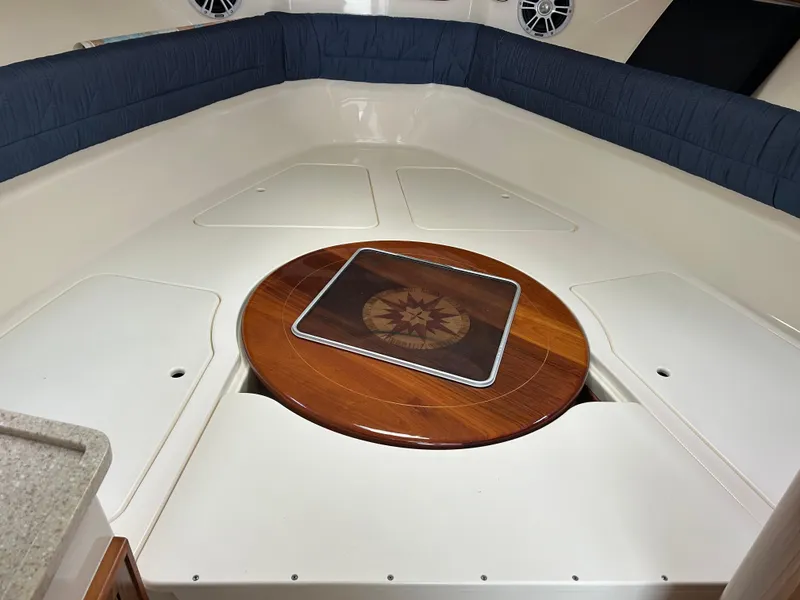 Slide: The Image of 2011 Pursuit OS 315 Offshore cabin interior with wooden table and cushioned seating. - 14