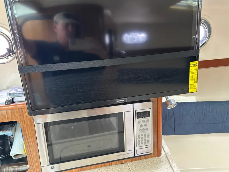 Slide: The Image of 2011 Pursuit OS 315 Offshore interior with TV and microwave setup. - 15