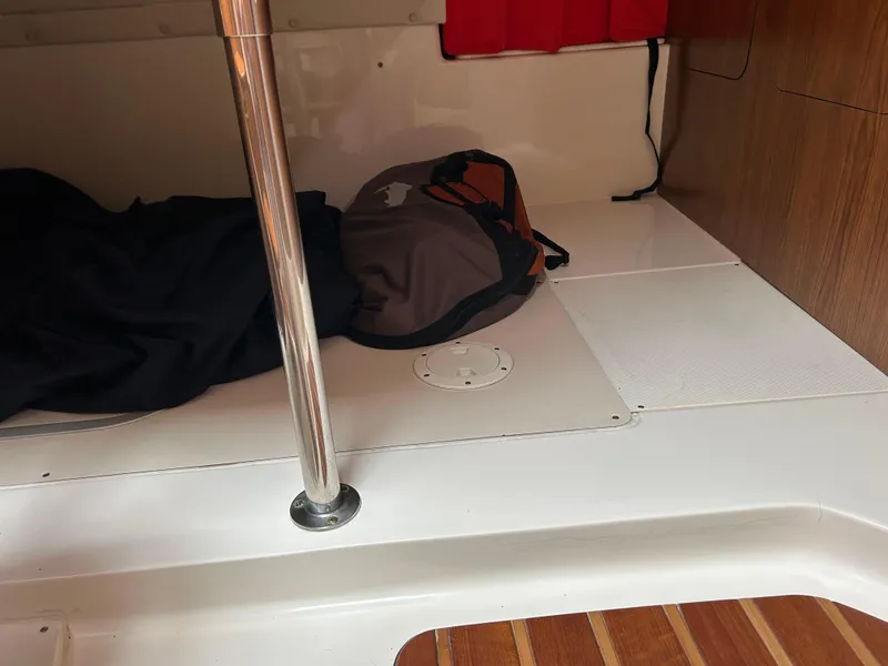 Slide: The Image of Interior of a 2011 Pursuit OS 315 Offshore boat, featuring a cabin area with a bag and pole. - 18