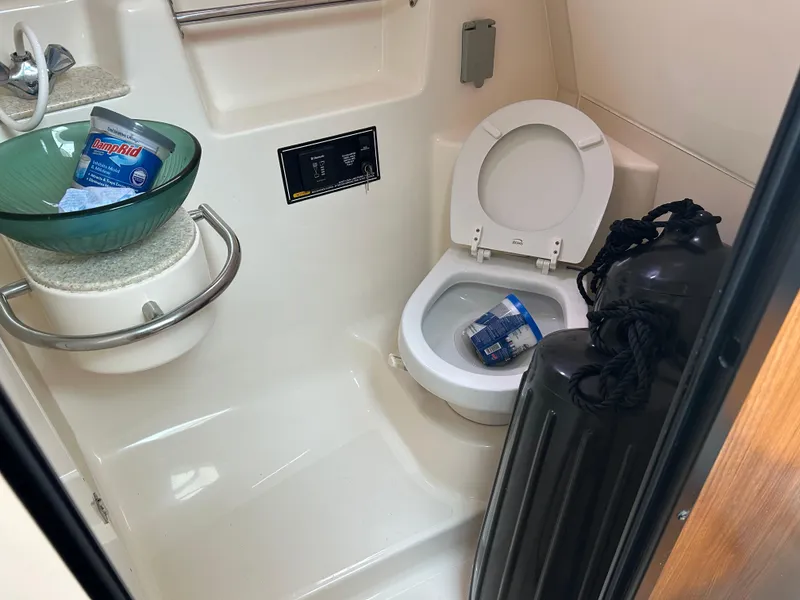 Slide: The Image of 2011 Pursuit OS 315 Offshore bathroom with toilet, sink, and storage items. - 19
