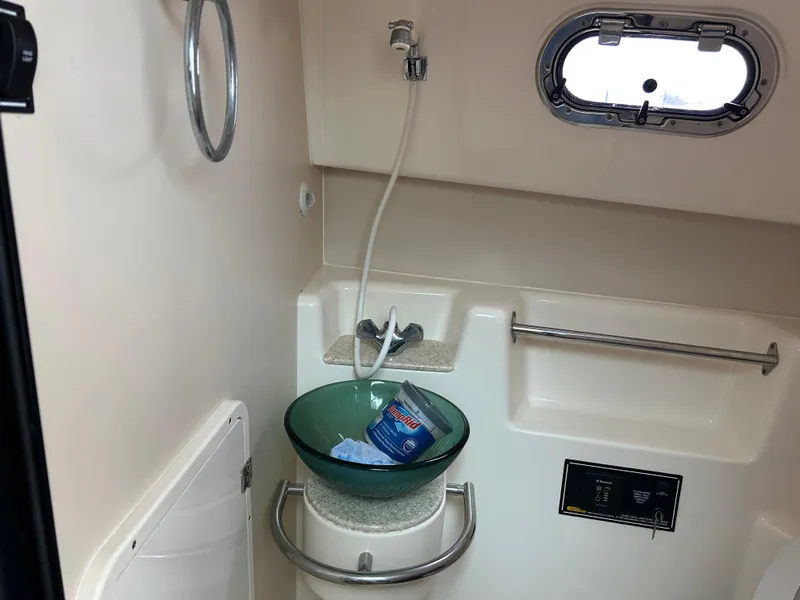 Slide: The Image of 2011 Pursuit OS 315 Offshore bathroom with sink, shower, and porthole window. - 20