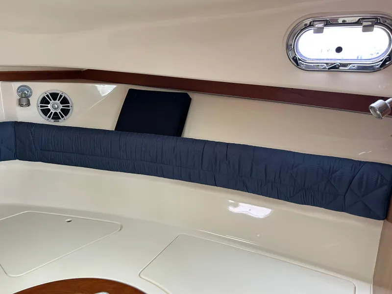 Slide: The Image of Interior cabin of 2011 Pursuit OS 315 Offshore boat with cushioned seating and porthole. - 21