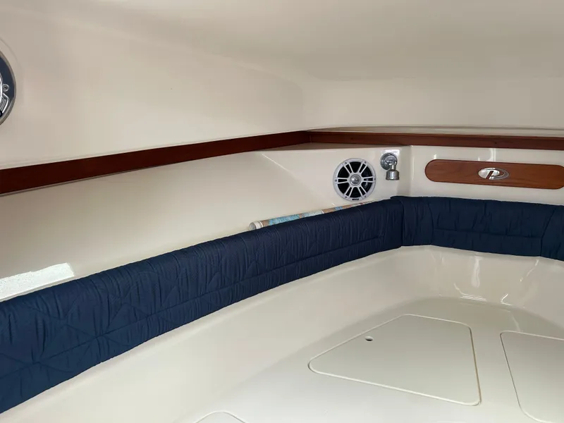 Slide: The Image of 2011 Pursuit OS 315 Offshore cabin interior with blue cushioned seating and wood accents. - 22