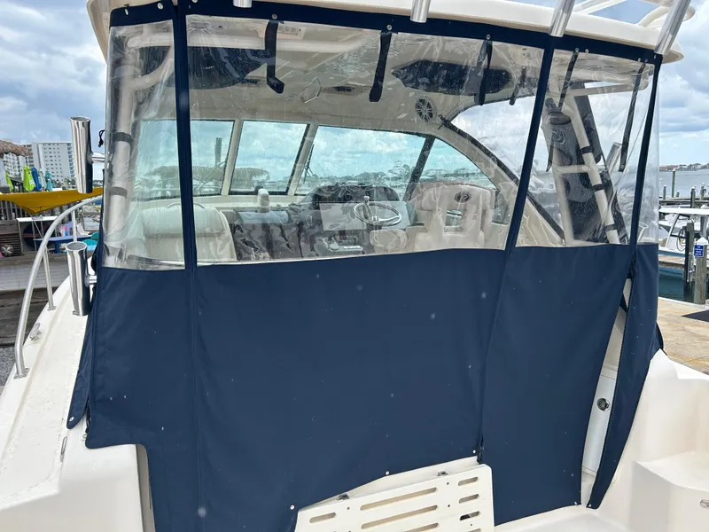 Slide: The Image of 2011 Pursuit OS 315 Offshore boat with blue canvas enclosure at a marina. - 5