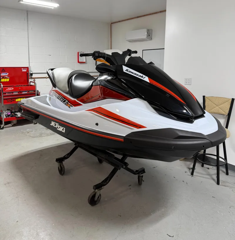 Slide: The Image of 2025 Kawasaki STX 160X jet ski in a garage, showcasing sleek design and vibrant colors. - 1