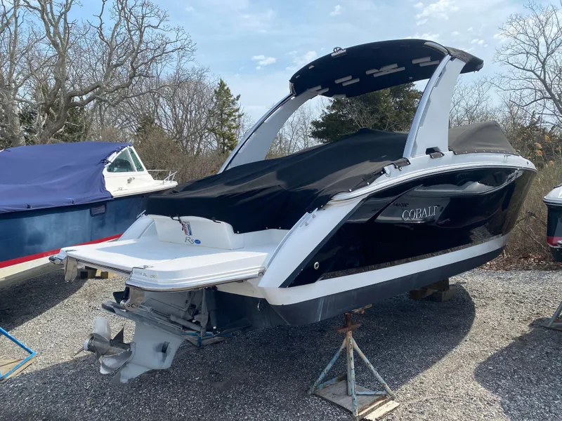 Slide: The Image of 2018 Cobalt R5 boat on stands, covered, with trees in the background. - 0