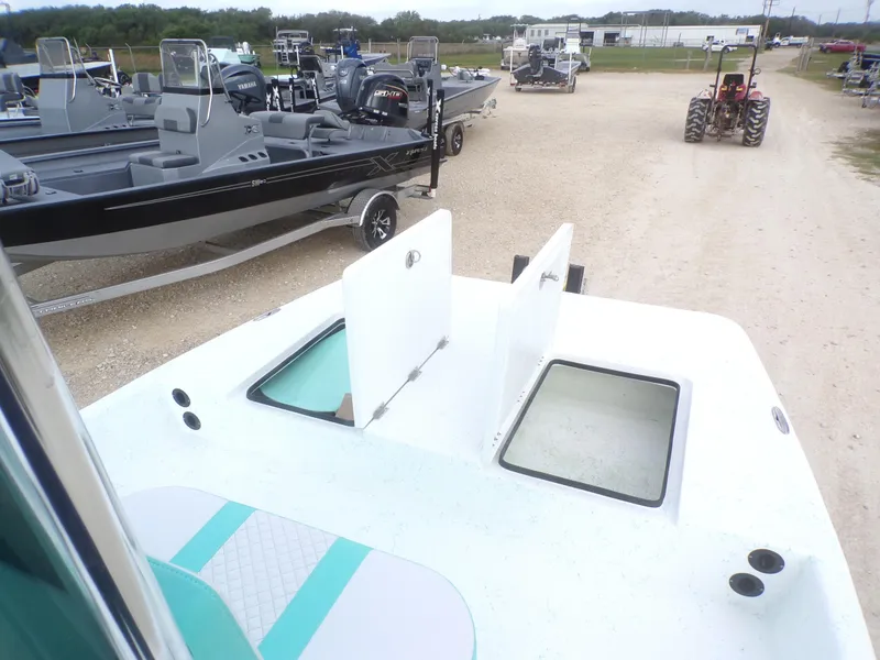 Slide: The Image of 2025 Freedom Eagle 16 boat with open storage compartments, parked near other boats and a tractor. - 19