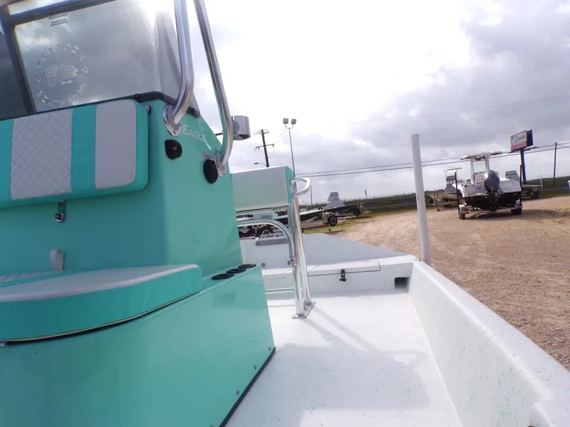 Slide: The Image of 2025 Freedom Eagle 16 boat with teal accents, parked outdoors on a cloudy day. - 25
