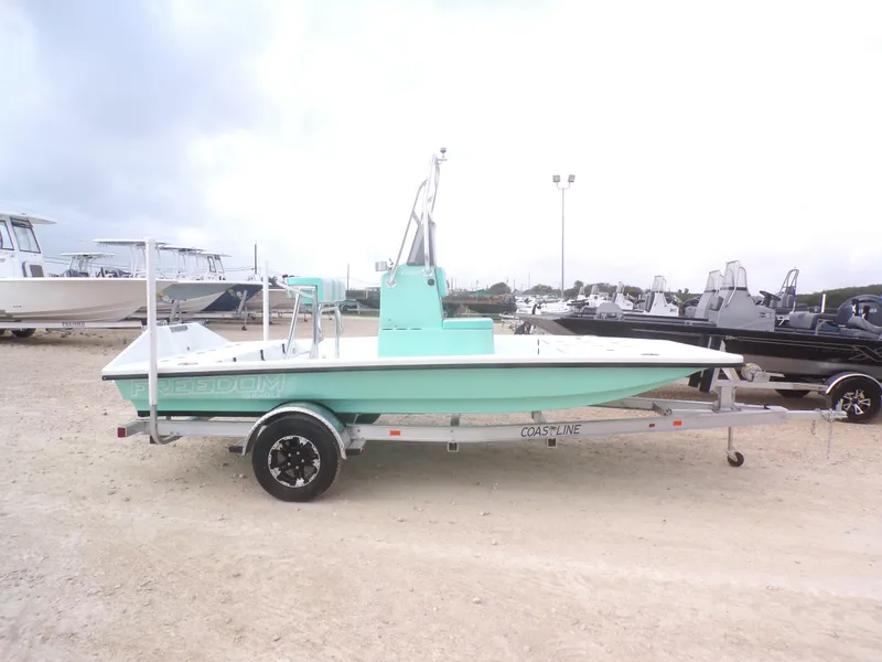 Slide: The Image of 2025 Freedom Eagle 16 boat on trailer, mint green hull, parked outdoors. - 8