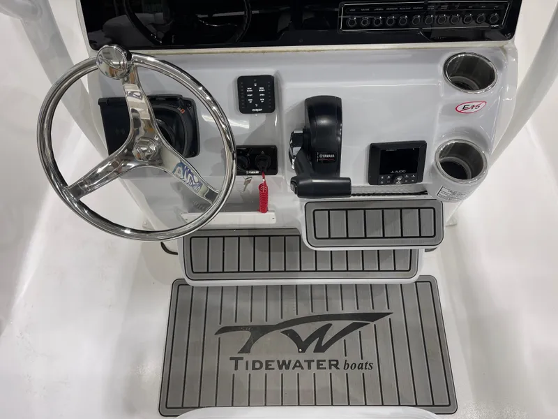 Slide: The Image of 2025 Tidewater 220LXF boat console with steering wheel, controls, and branded mat. - 20