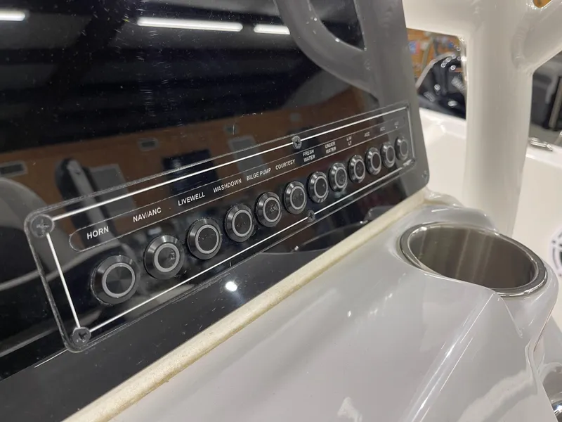 Slide: The Image of Control panel of 2025 Tidewater 220LXF boat with labeled buttons and cup holder. - 23