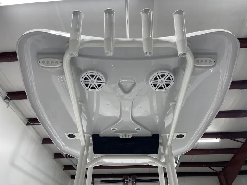 Slide: The Image of 2025 Tidewater 220LXF boat T-top with rod holders and speakers in a garage. - 26