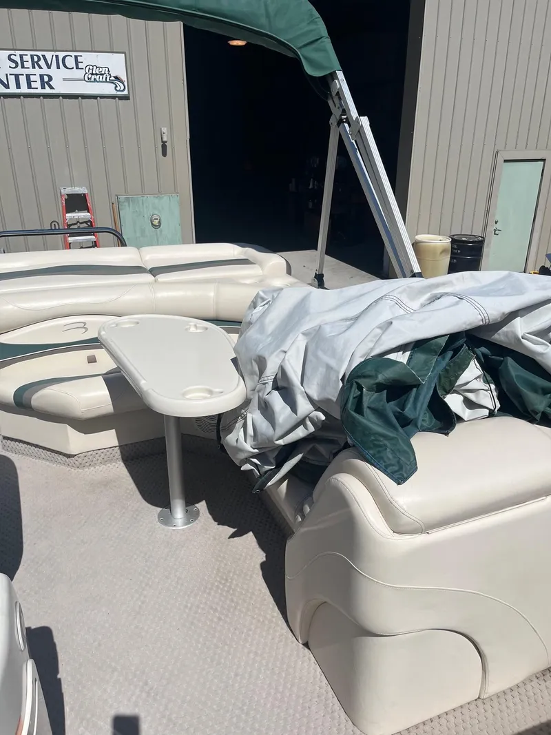 Slide: The Image of 2004 Bennington 2250 RL pontoon boat interior with seating and table, near service center. - 4
