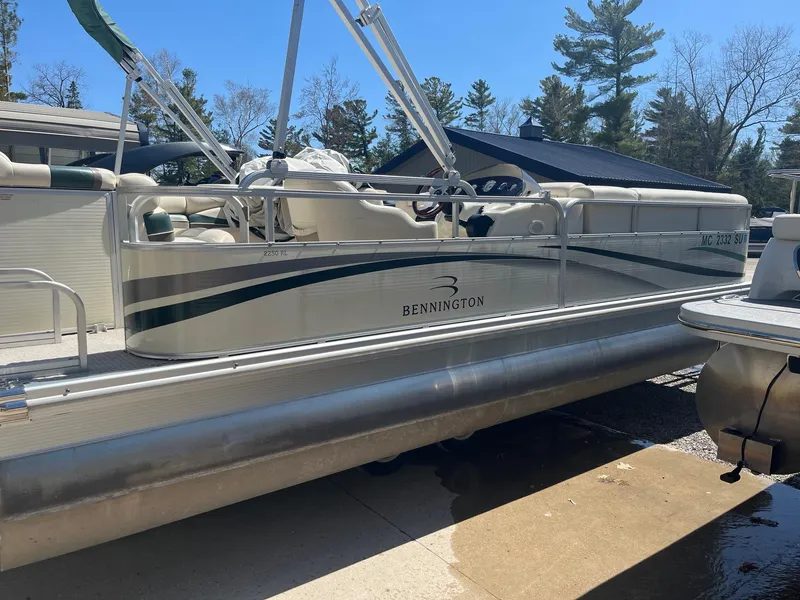 Slide: The Image of 2004 Bennington 2250 RL pontoon boat on trailer, surrounded by trees and clear sky. - 5