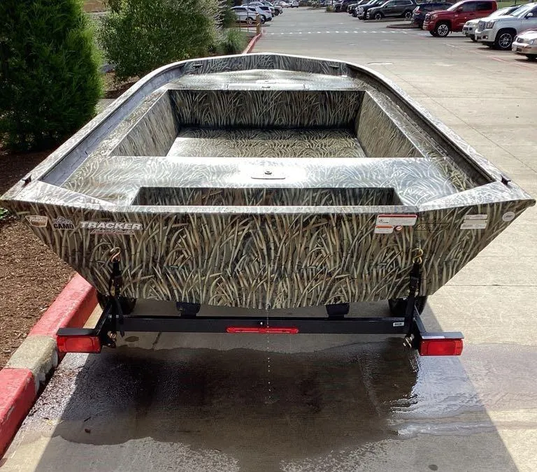 Slide: The Image of 2025 Tracker GRIZZLY 1860 Utility boat on trailer, camo design, parked outdoors. - 6
