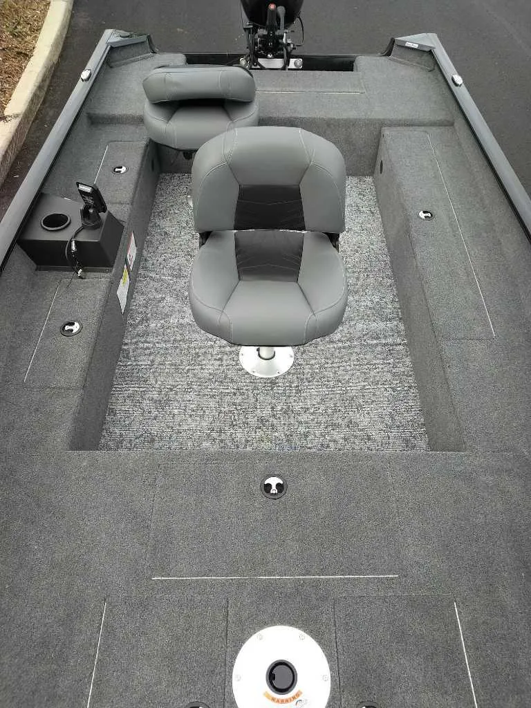 Slide: The Image of 2025 Tracker Super Guide V-16 T boat interior with gray seating and carpeted deck. - 2