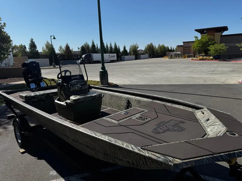 Slide: The Image of 2025 Tracker Grizzly 1860 CC boat parked outdoors on a sunny day. - 2