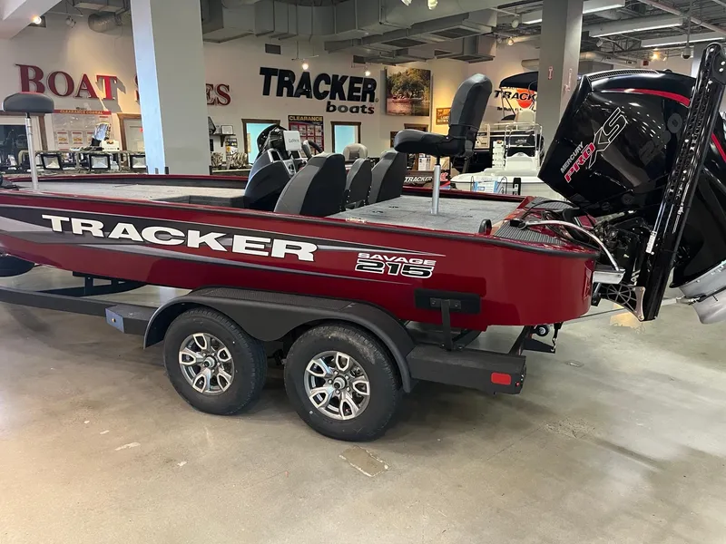 Slide: The Image of 2025 Tracker Savage 215 boat in showroom, red exterior, dual-axle trailer, powerful outboard motor. - 3