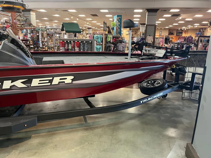 Slide: The Image of 2025 Tracker Savage 215 boat displayed indoors, surrounded by retail merchandise. - 5
