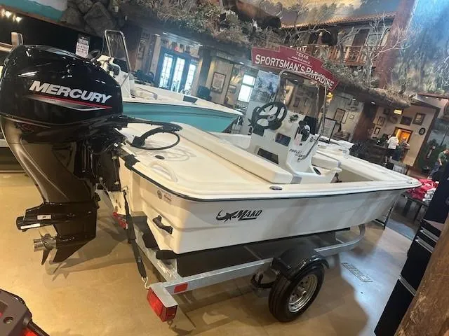 Slide: The Image of 2025 Mako Pro Skiff 13 CC boat with Mercury engine on display indoors. - 3