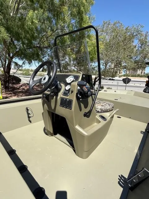 Slide: The Image of 2025 Tracker Grizzly 1860 CC boat console with steering wheel, outdoors under clear sky. - 6