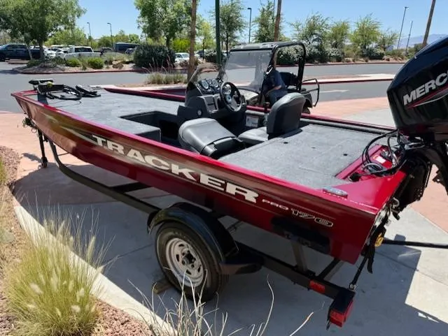 Slide: The Image of 2025 Tracker Pro 170 boat with Mercury engine, parked outdoors on a sunny day. - 2