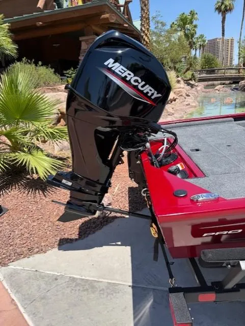 Slide: The Image of 2025 Tracker Pro 170 boat with Mercury outboard motor, parked near tropical landscaping. - 4