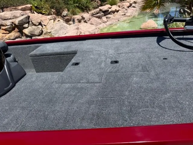 Slide: The Image of 2025 Tracker Pro 170 boat deck with gray carpet and red trim, near rocky landscape. - 7