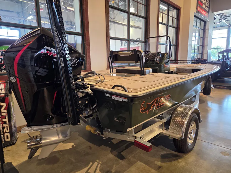 Slide: The Image of 2025 Mako 18 Pro Skiff Backwater Edition boat displayed indoors with powerful outboard motor. - 2