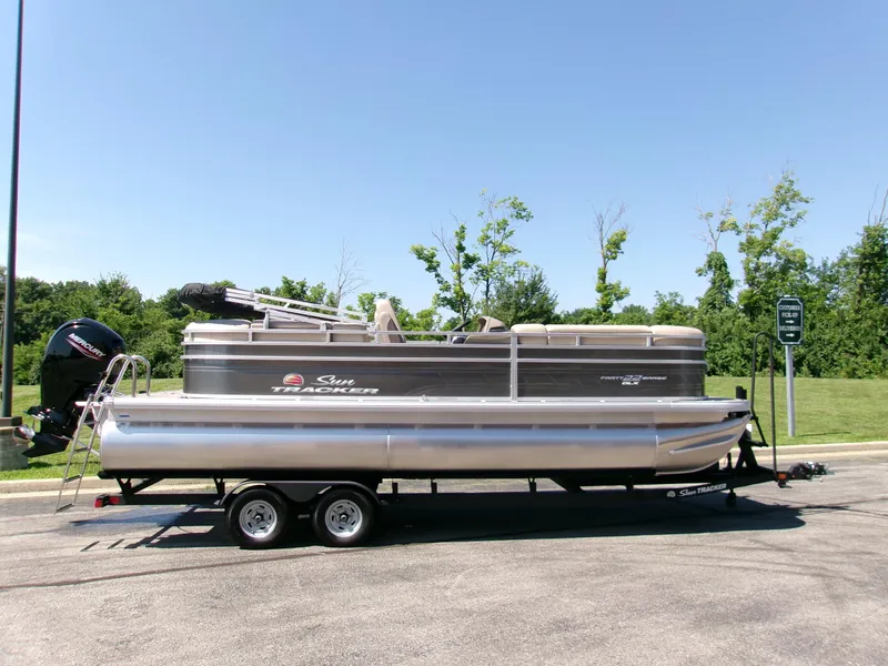 The Image of 2025 Sun Tracker Party Barge 22 DLX pontoon boat on trailer, parked outdoors. - 0