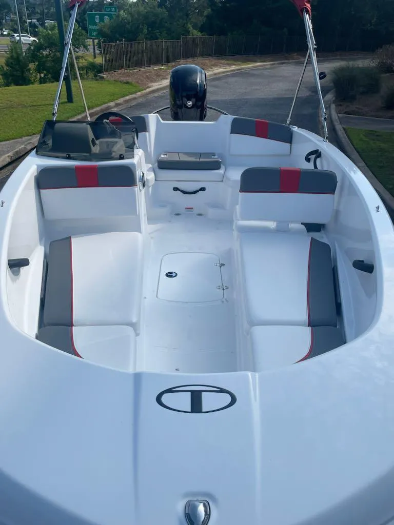 Slide: The Image of 2025 Tahoe T16 boat interior with seating and steering, docked outdoors. - 2